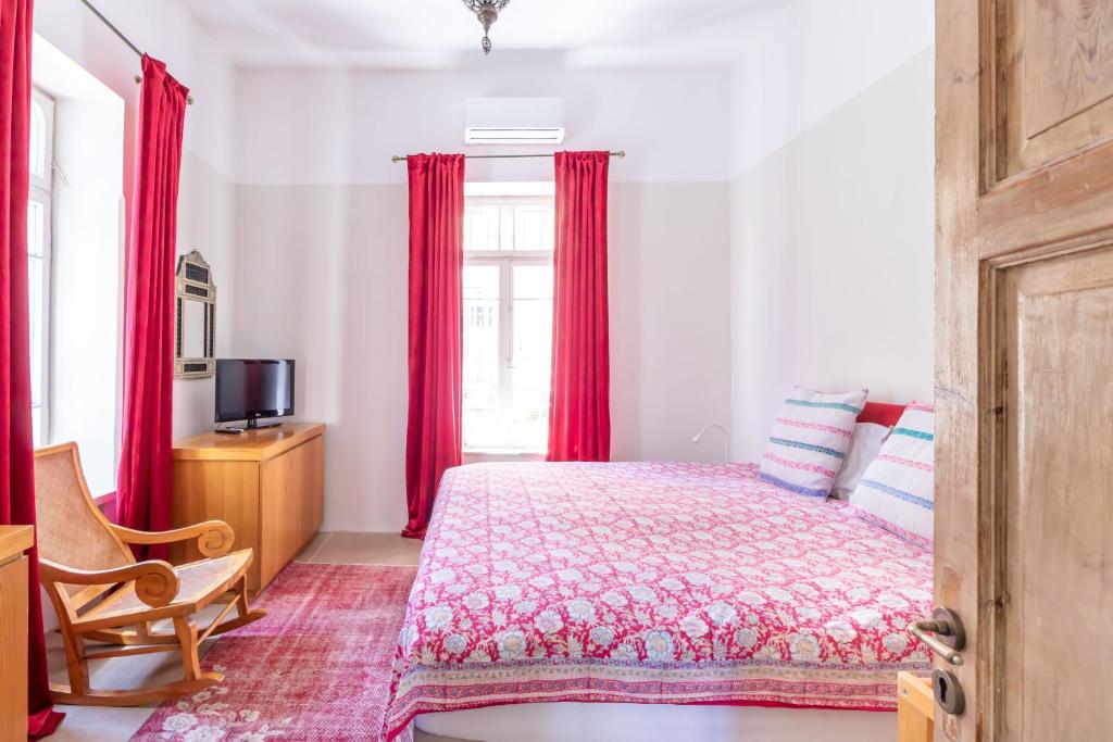 耶路撒冷塔比耶珍宝全新公寓的一间卧室配有床和红色窗帘的窗户