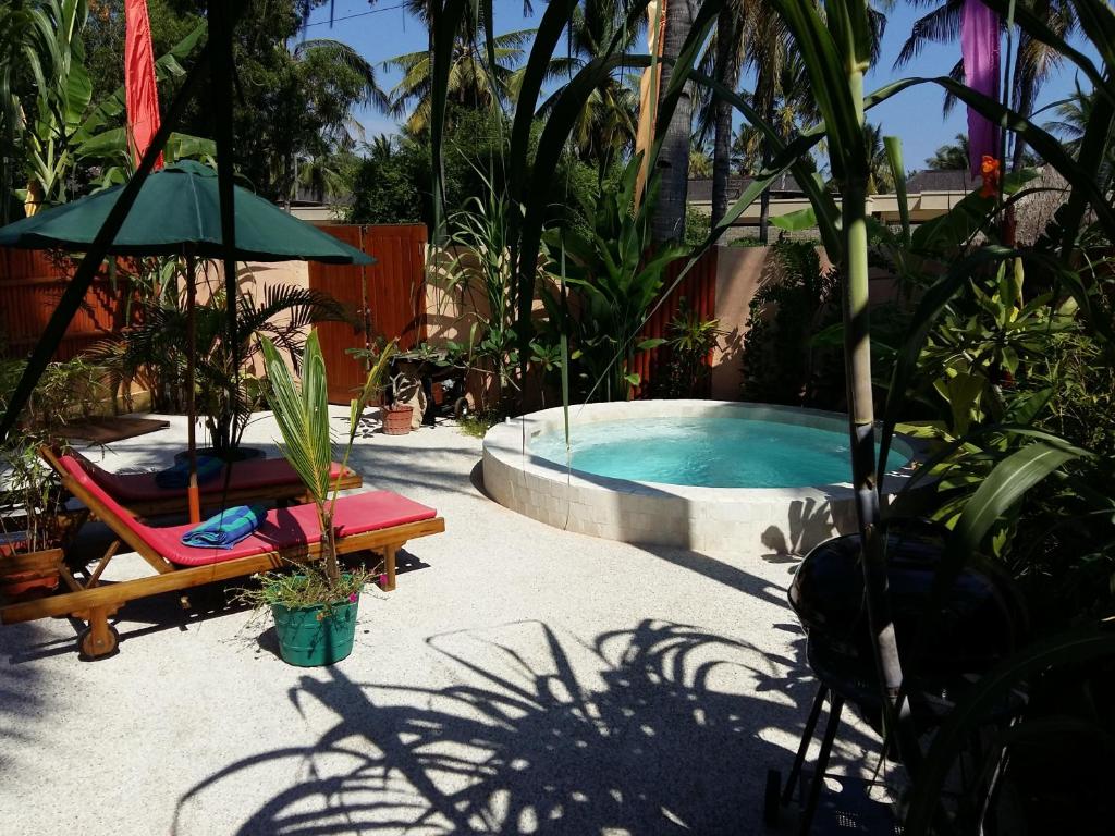 吉利特拉旺安三潭吉利小屋酒店的游泳池配有椅子、遮阳伞和四柱床
