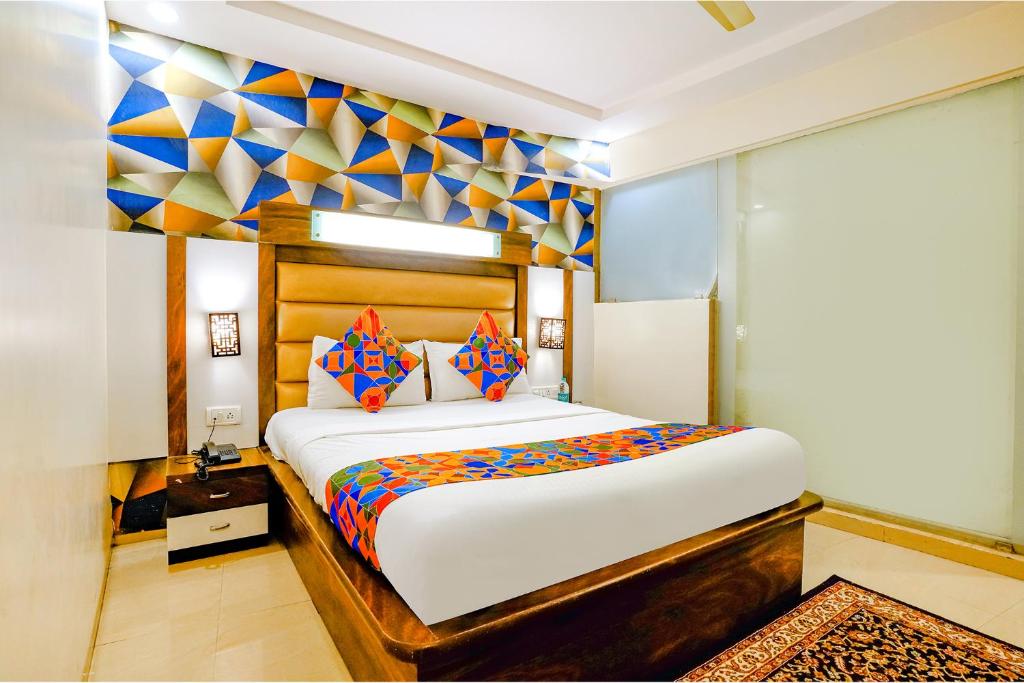 孟买FabHotel Kwality Inn的一间卧室设有一张大床和色彩缤纷的墙壁