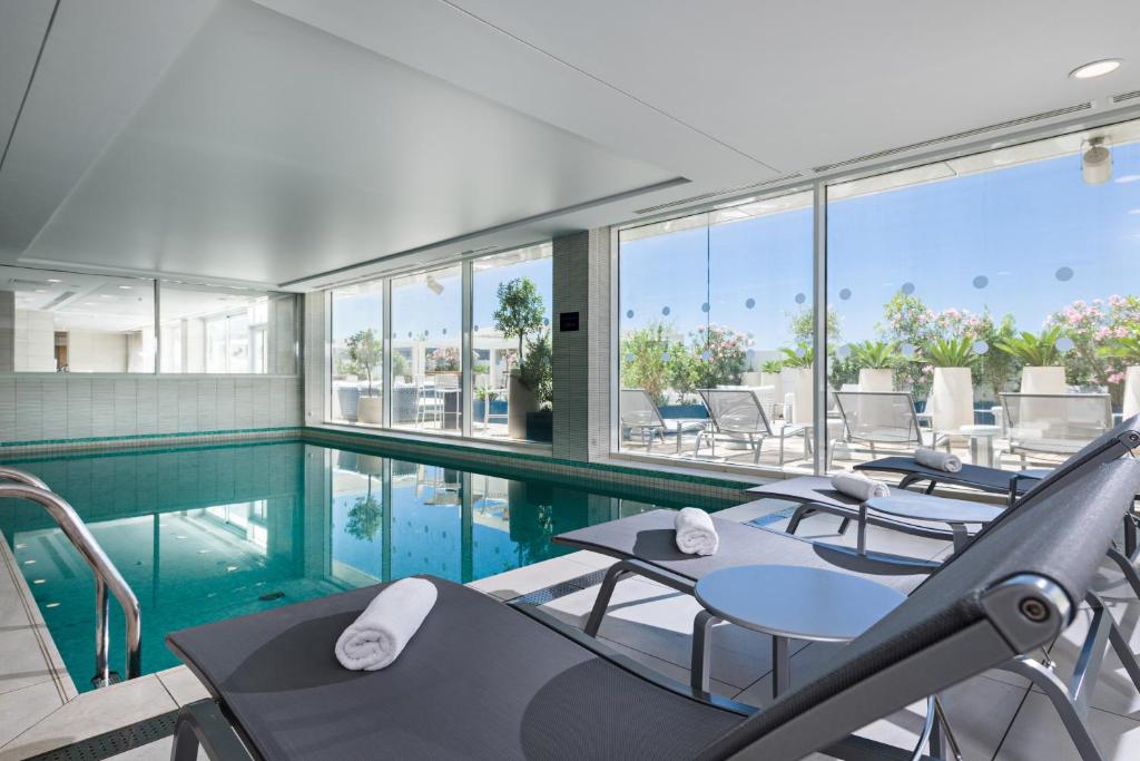 马赛马赛欧洲地中海金色郁金香酒店的大楼内带桌椅的游泳池