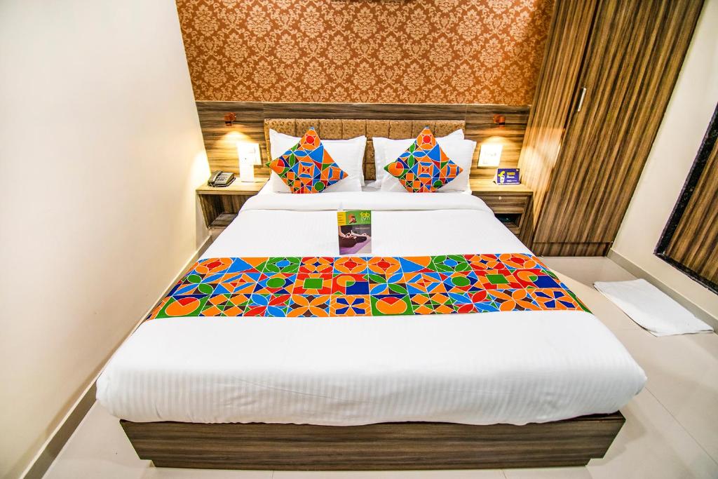 孟买FabExpress Orange Suite的酒店客房配有带丰富多彩枕头的床。
