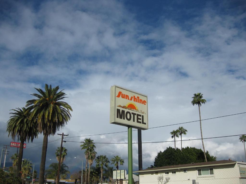 圣贝纳迪诺阳光汽车旅馆的棕榈树建筑前的汽车旅馆标志
