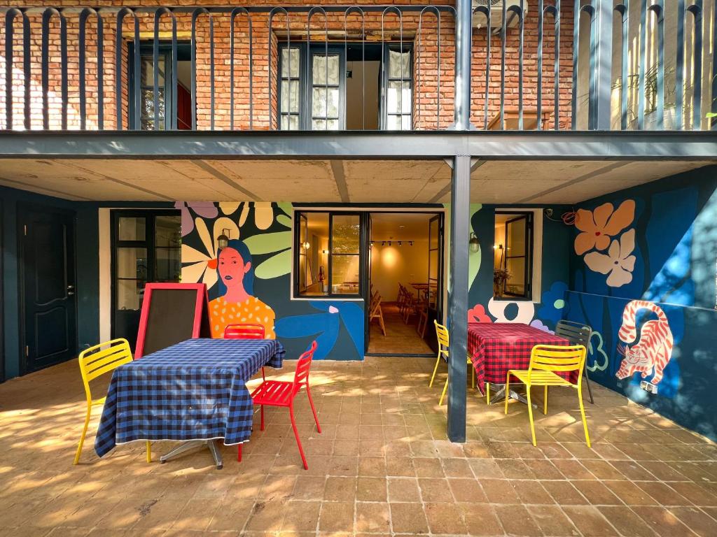 库塔伊西Black Tomato Hostel Kutaisi的一个带桌椅和壁画的庭院