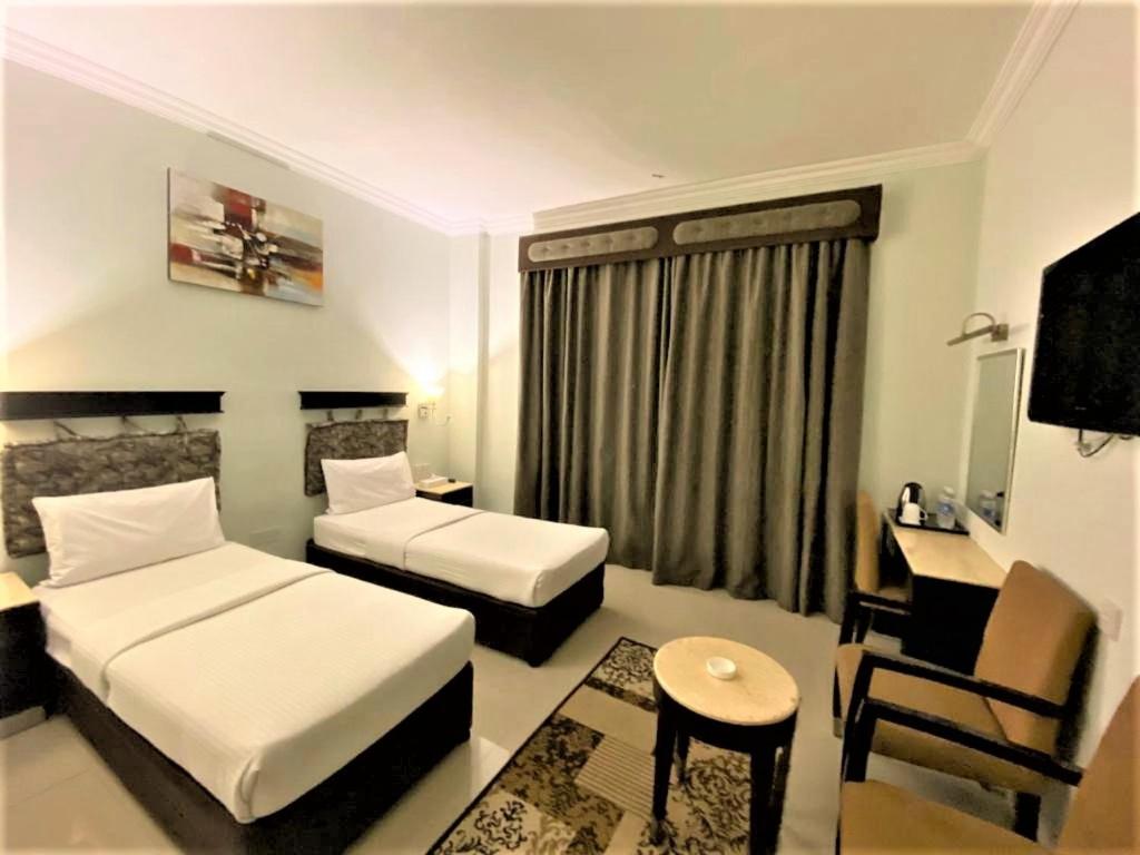 迪拜Signature Inn Hotel - Free Parking的酒店客房配有两张床和一张书桌