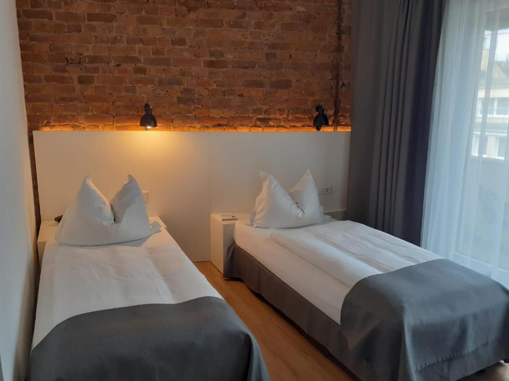 杜塞尔多夫林德霍夫酒店的砖墙客房的两张床