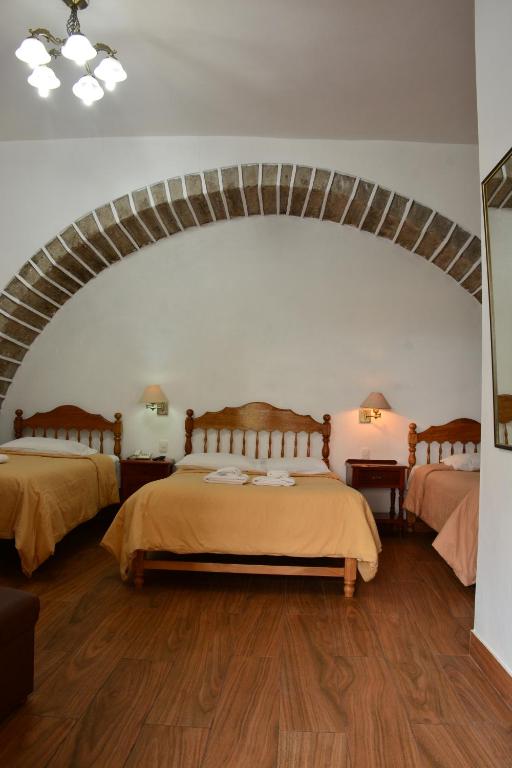 阿亚库乔Hotel Santa Rosa的一间带两张床铺的卧室,位于带拱门的房间