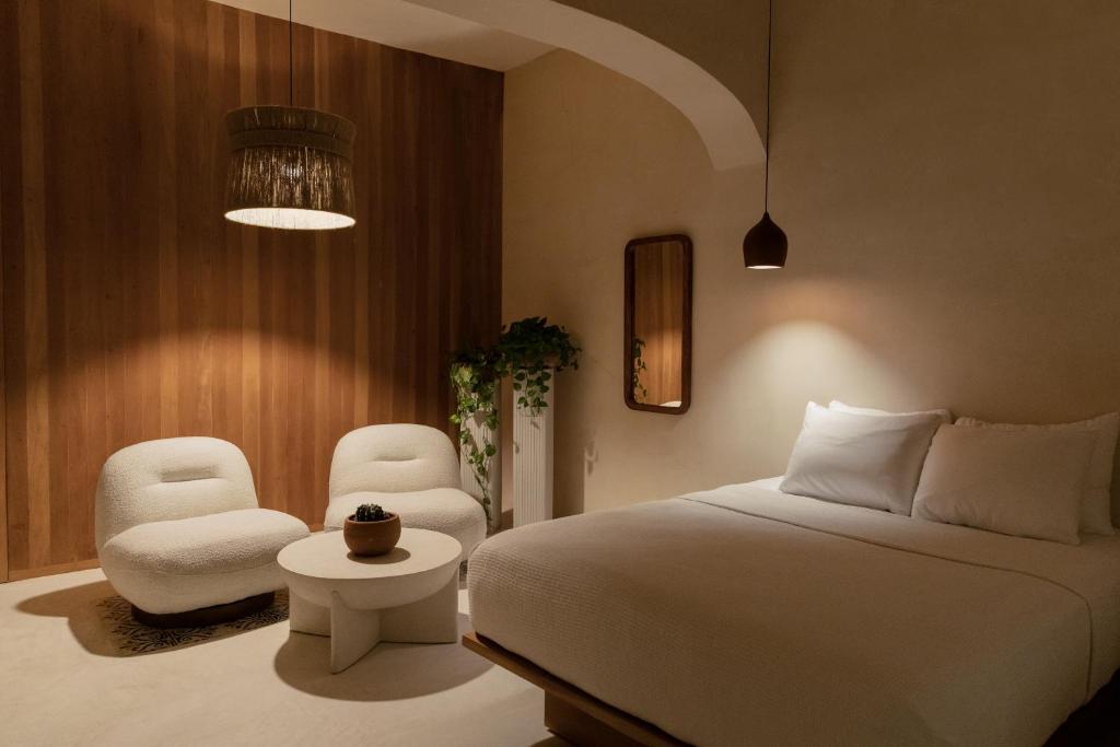 坎佩切Narrativ Lofts - Lira - Mid Century Cozy Retreat的一间卧室配有一张床和两把椅子