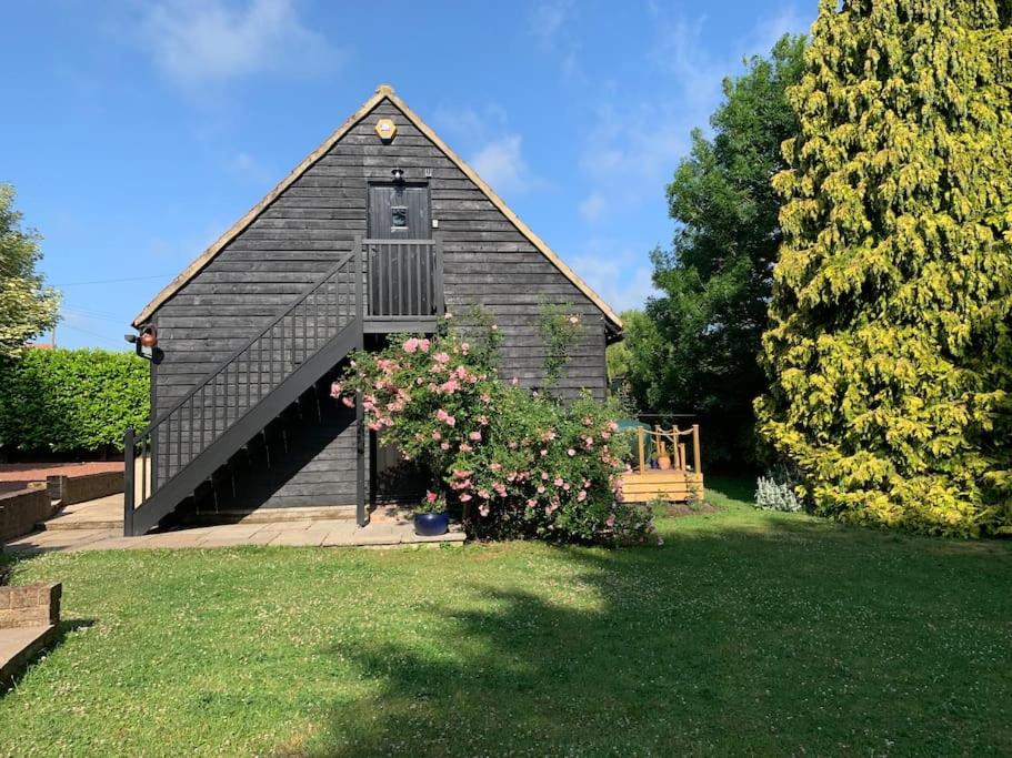 朗梅尔福德Newly converted 2 storey, 2 bedroom, barn in Long Melford的一座黑色屋顶和灌木的小教堂