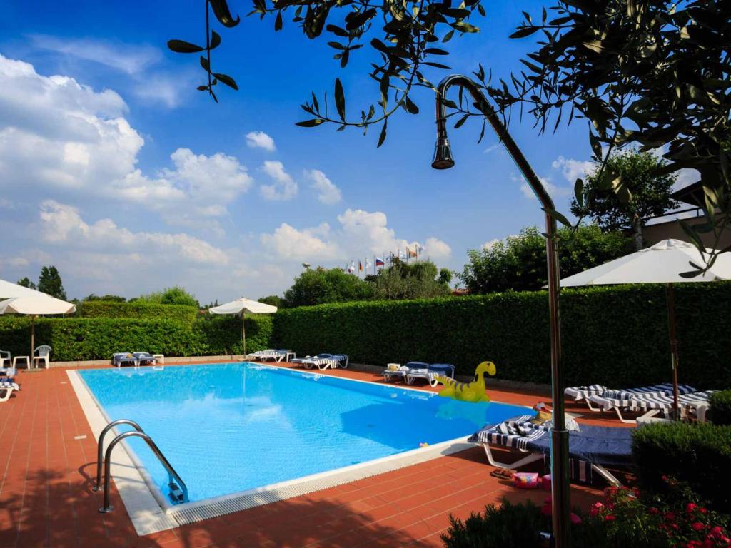 西尔米奥奈贝拉西尔米奥奈假日公寓式酒店的一个带椅子和遮阳伞的大型游泳池