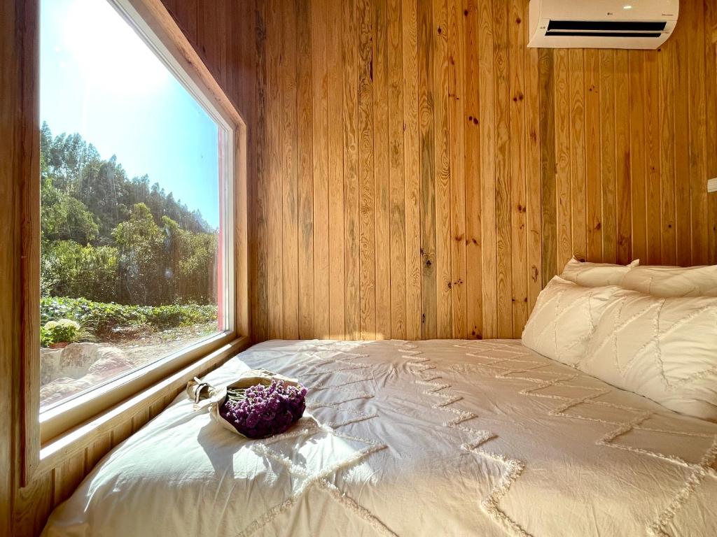 CelaNativo Natureza Pink Wood Cabin的一间卧室设有一张大床和大窗户