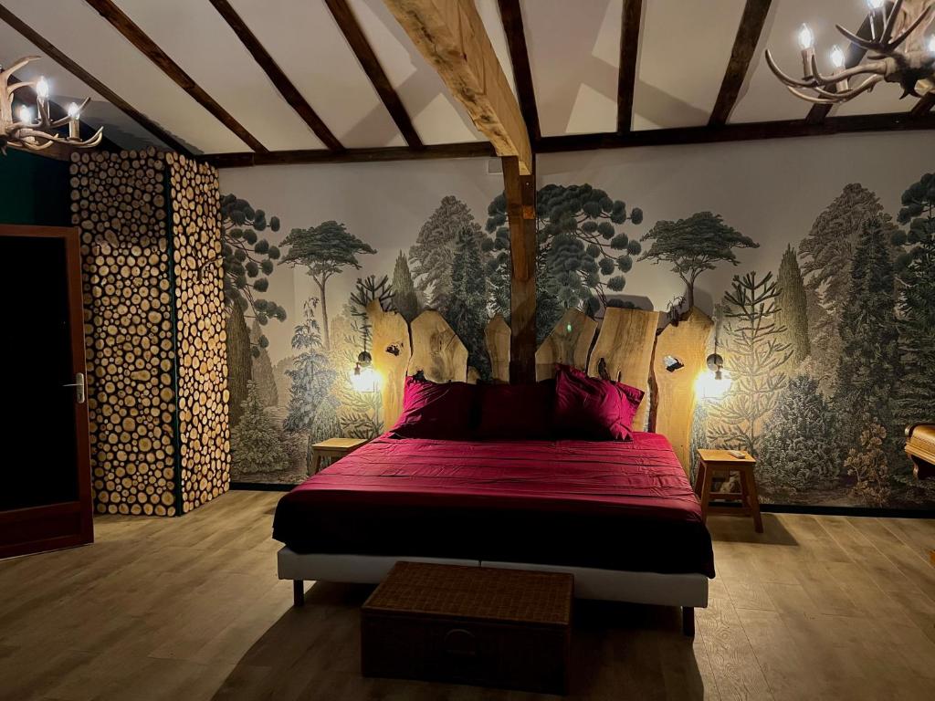奥普La cabane de babarot的卧室配有一张铺有红床单的床,墙上挂着树木