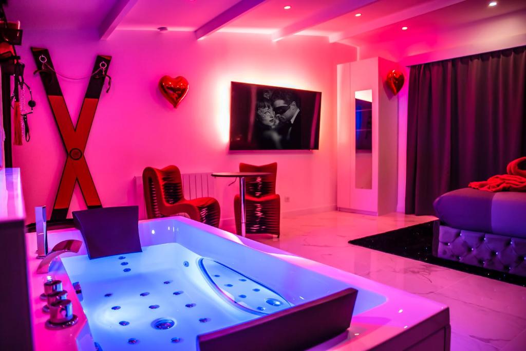 奥尔日河畔布雷蒂尼SECRET SUITE "Mr Grey" - Jacuzzi privatif - Gare RER C - Proche Paris的粉红色的客房设有浴缸和床。