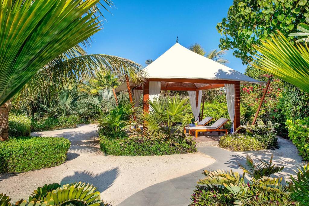 拉斯阿尔卡麦拉斯阿尔卡麦海滩悦榕庄酒店的花园设有凉亭、椅子和植物