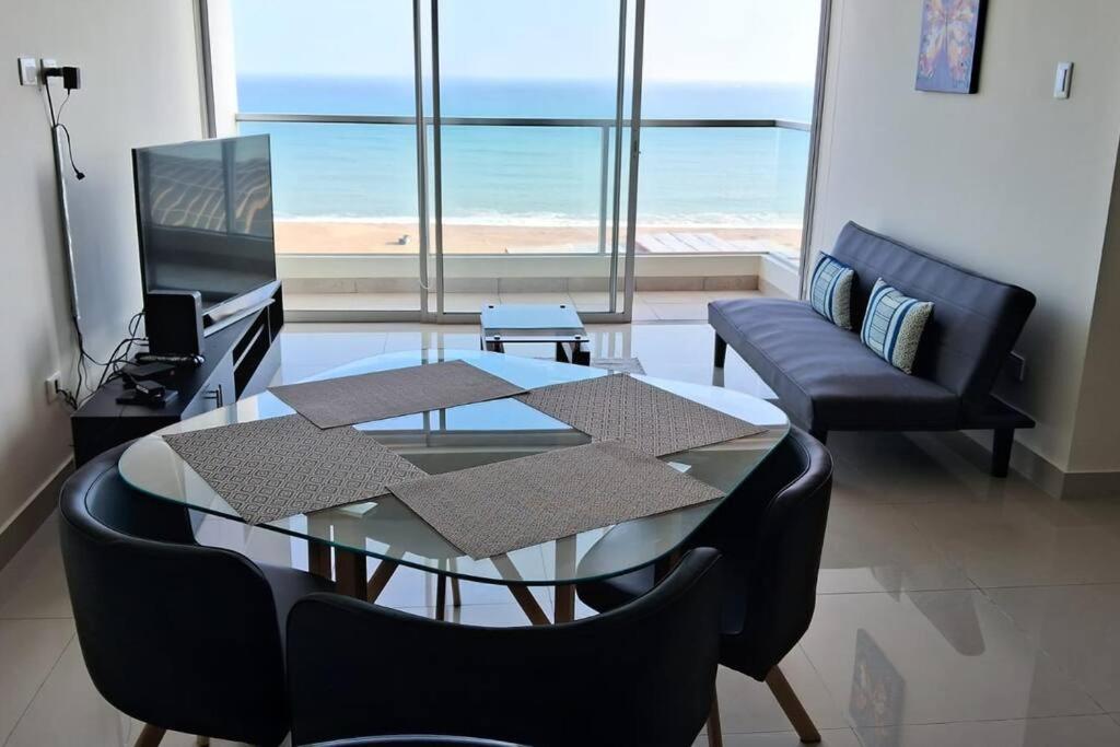 利马apartamento de estreno con balcón frente al mar.的客厅配有玻璃桌和椅子