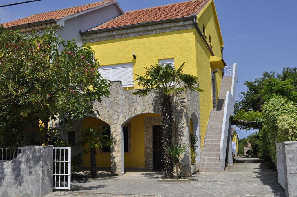 利纳迪奇Apartments Pavlović的一座黄色房子,前面有一棵棕榈树