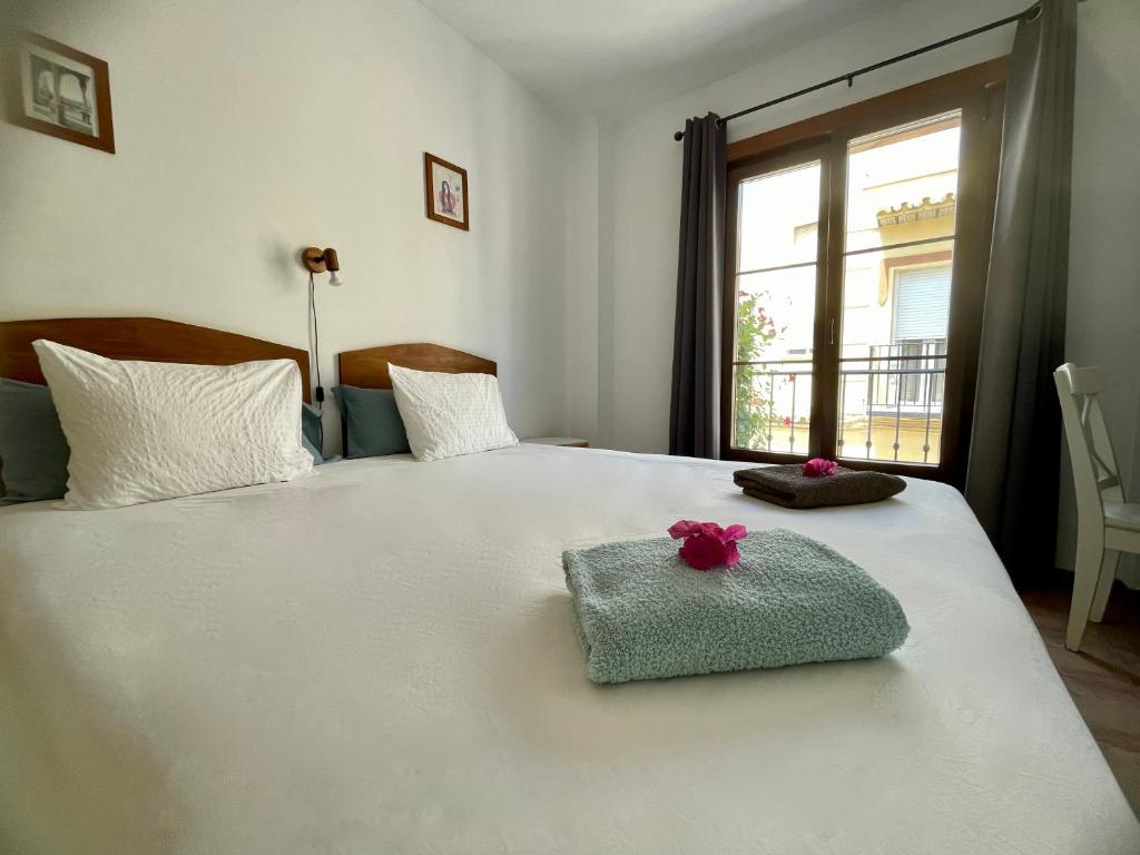 内尔哈Boutique Hostal Lorca的卧室配有带毛巾的白色床和窗户。
