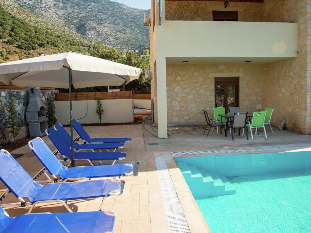 巴利恩Luxurious Villa in Bali Crete with Pool的游泳池配有椅子、遮阳伞和桌子