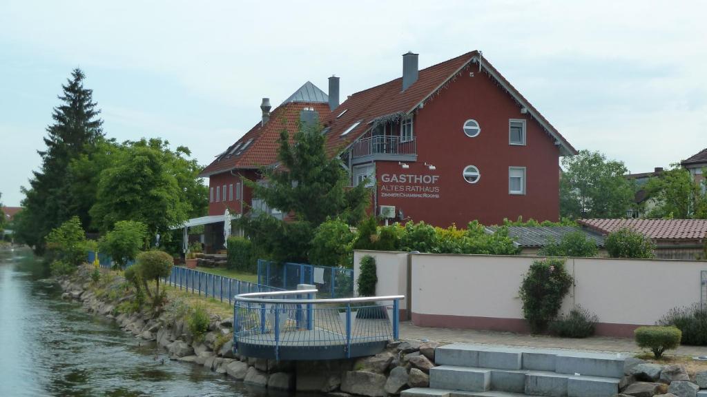 鲁斯特Gasthof Altes Rathaus garni的河边的红色建筑,有房子
