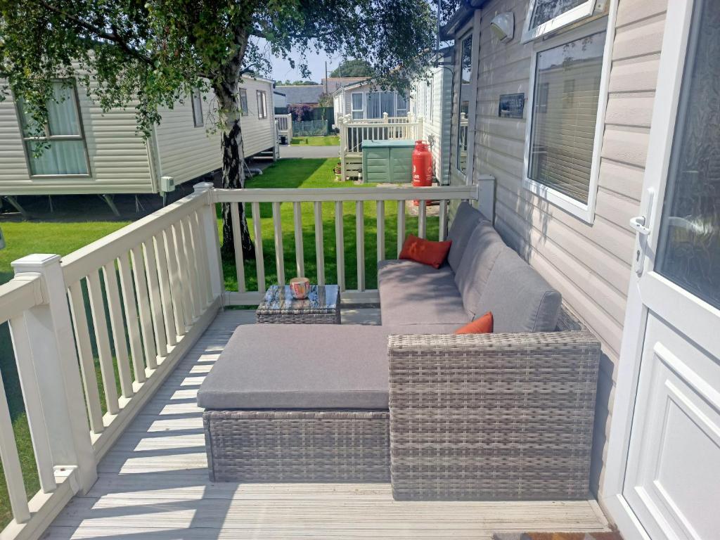 普利斯坦丁2 Bedroom Static Caravan C3 on quiet park near Talacre and Prestatyn的房屋一侧带沙发的门廊