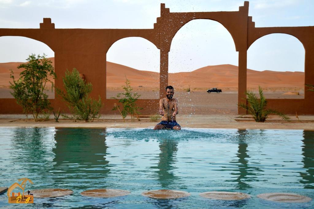梅尔祖卡Kasbah Du Berger & Piscine的坐在沙漠水库中的男人