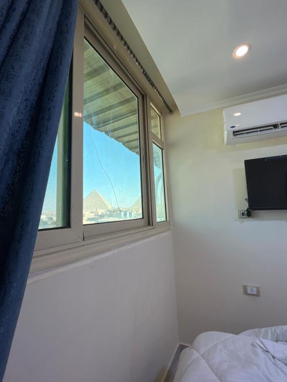 开罗Pyramids Pride Inn的卧室设有窗户、一张床和一台电视