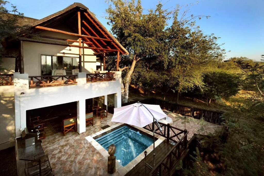 玛洛斯帕克Eden Safari Country House的一座带游泳池和遮阳伞的房子