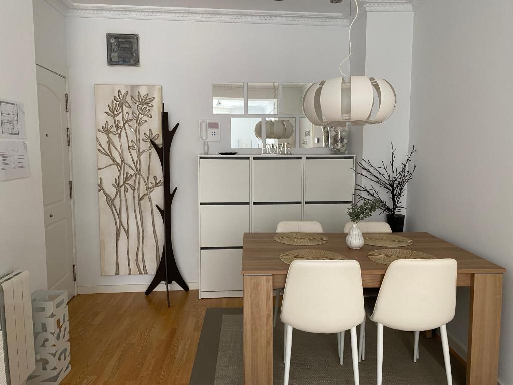 毕尔巴鄂Apartamento Lea的一间带木桌和白色椅子的用餐室
