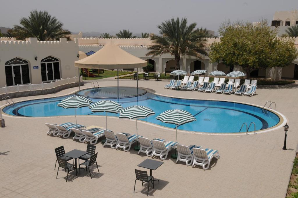 尼兹瓦法拉达里斯酒店的一个带椅子和遮阳伞的游泳池以及一组设施