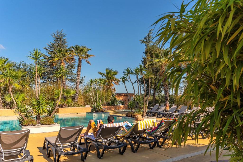 滨海阿热莱斯魔松树露营酒店的一群人坐在游泳池边的椅子上