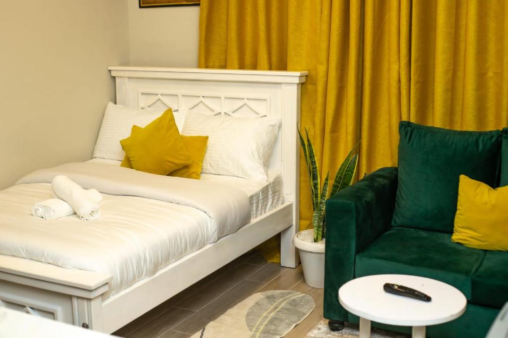 思由基茅Indesign Makumbi park studio Apartment D4-5,Syokimau的卧室配有白色的床和绿色椅子