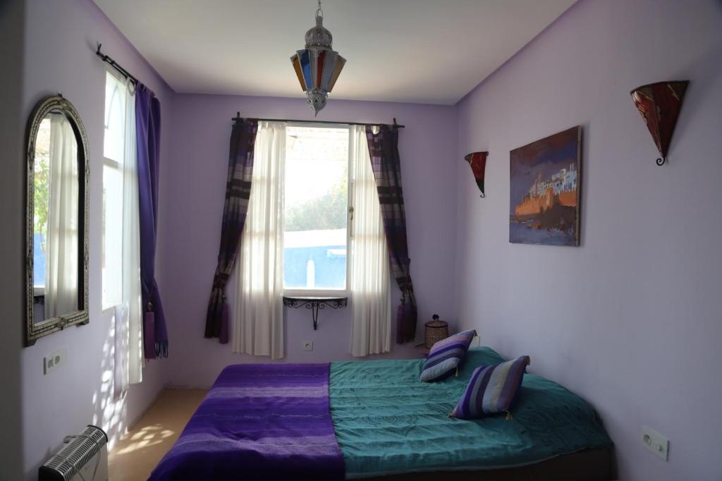 索维拉Villa aloe vera的一间卧室配有一张带紫色床单的床和窗户。