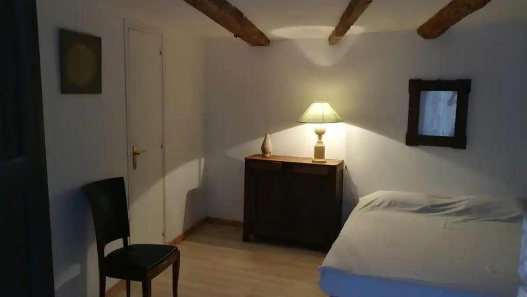 芒通VieuxChateau的一间卧室配有一张床、一盏灯和一把椅子