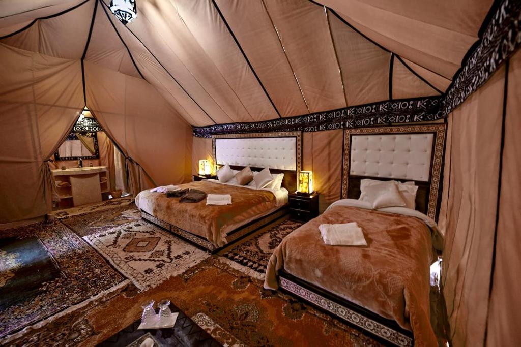 梅尔祖卡Ahlam Luxury Camp的一间帐篷内带两张床的卧室
