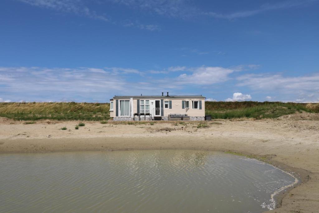 WolphaartsdijkDe Zuidvliet Chalet 4的海滩上一排水面上的白色房子