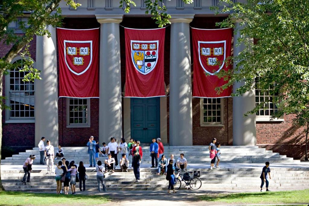 剑桥4 Bedroom Condo At Harvard Square and Harvard University的一群人走在一座有旗帜的建筑的台阶上