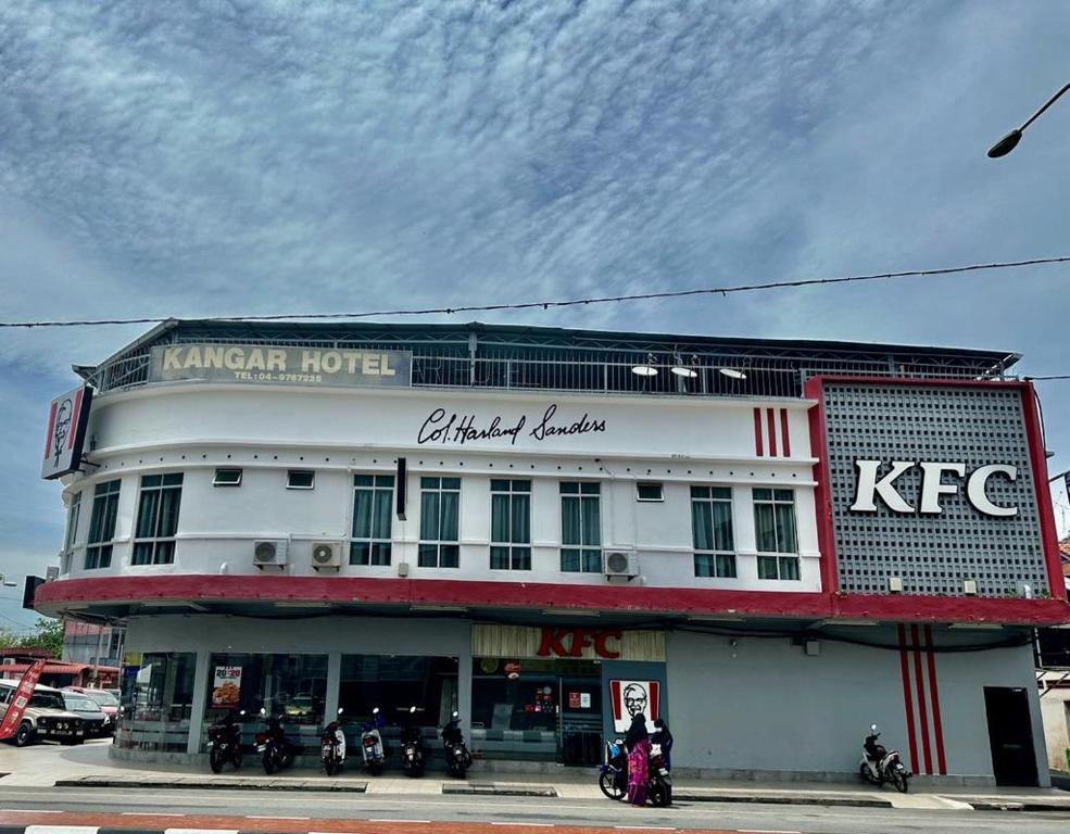 加央Kangar Hotel Sdn Bhd的一座白色的建筑,前面停有摩托车
