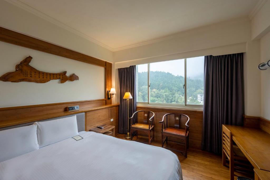 鹿谷乡孟宗山庄大饭店的配有一张床、一张书桌和一扇窗户的酒店客房