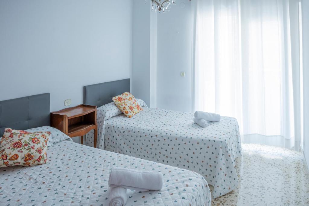 马拉加Apartamento Parque Mediterráneo的一间卧室设有两张床、一张桌子和窗户。