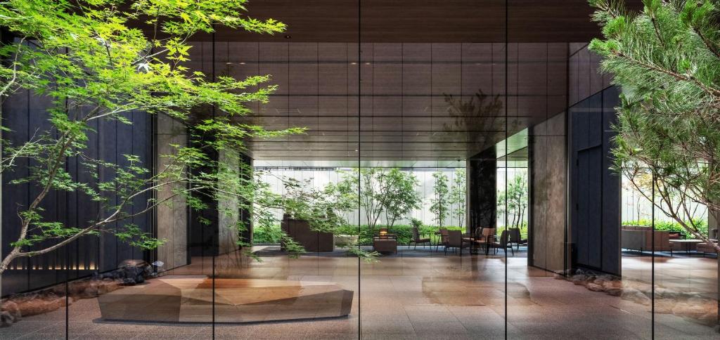 京都Richmond Hotel Premier Kyoto Shijo的一座拥有玻璃墙和树木的建筑的大堂