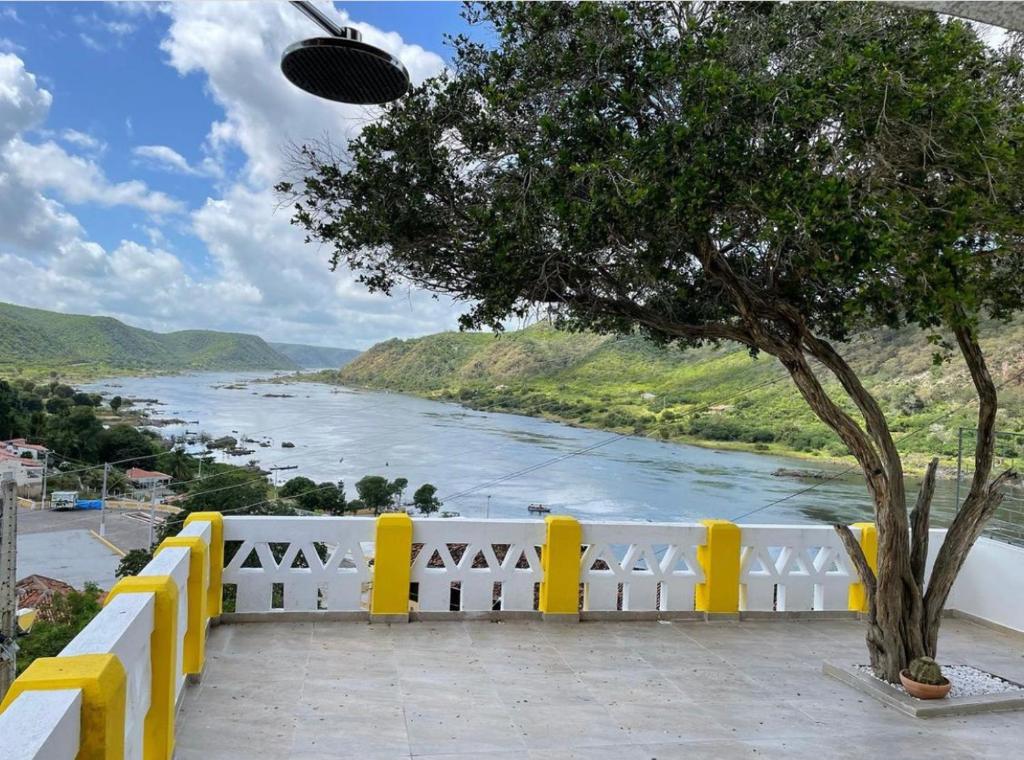 皮拉尼亚斯Casa Bela Vista的享有河流美景,设有黄色的栅栏和一棵树