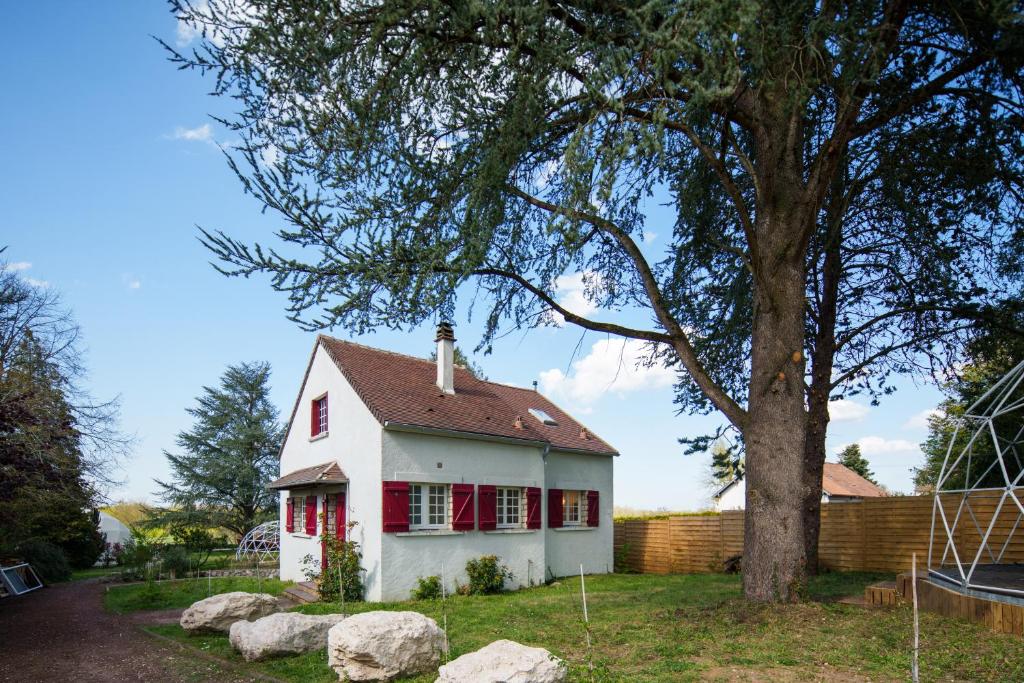 Saint-Dyé-sur-LoireMaison avec vue sur Loire proche de Chambord的一间白色的小房子,有红色的窗户和树