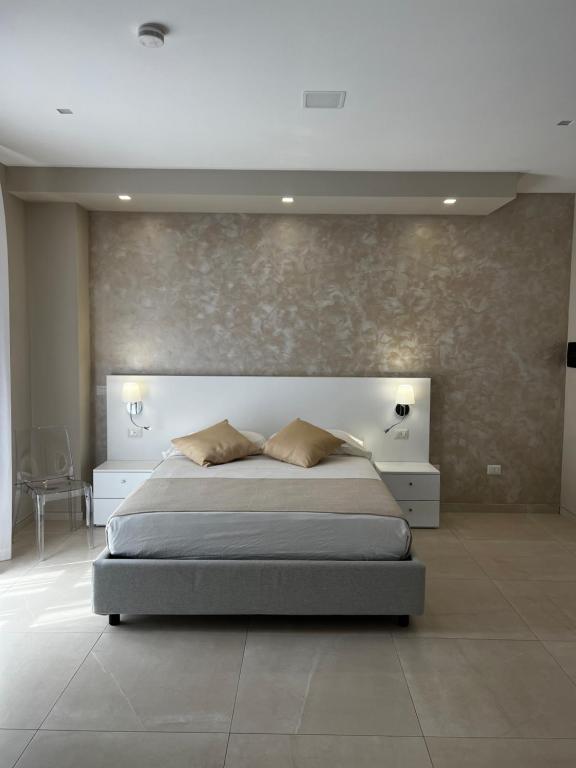 圣欧费米亚拉默齐亚B&B VIRGILIO LAMEZIA AIRPORT的一间卧室设有一张大床和一面墙