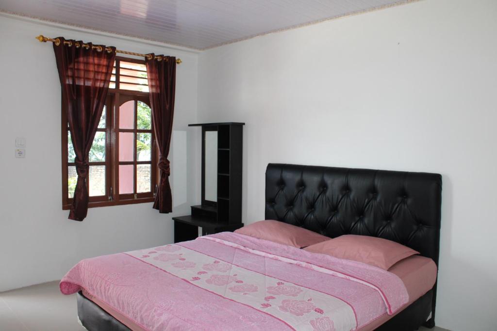 图克图克Hotel Barbara的一间卧室配有一张带粉色床单的床和一扇窗户。