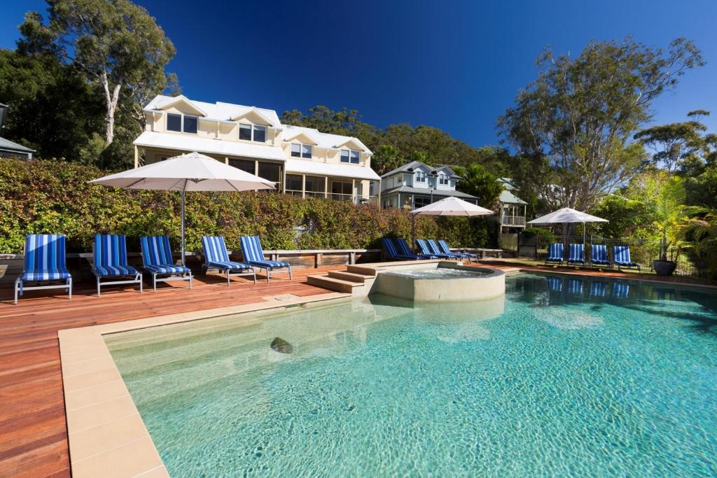 布鲁斯海滩布鲁耶斯酒店的房屋前的游泳池配有椅子和遮阳伞