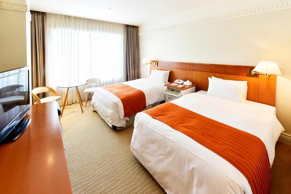 长崎THE GLOBAL VIEW Nagasaki的酒店客房设有两张床和一张桌子。