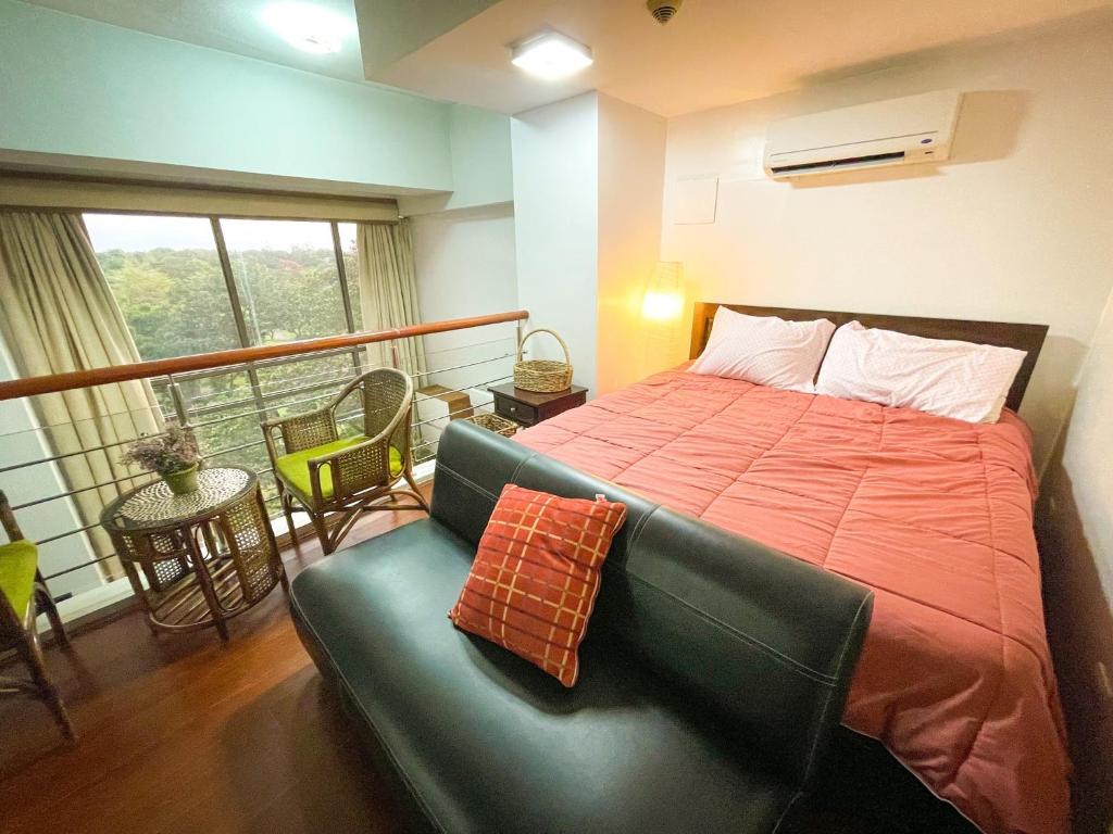 马尼拉Lovely 1BR Loft in BGC up to 6pax的一间卧室配有一张床和一张沙发,并设有一个阳台