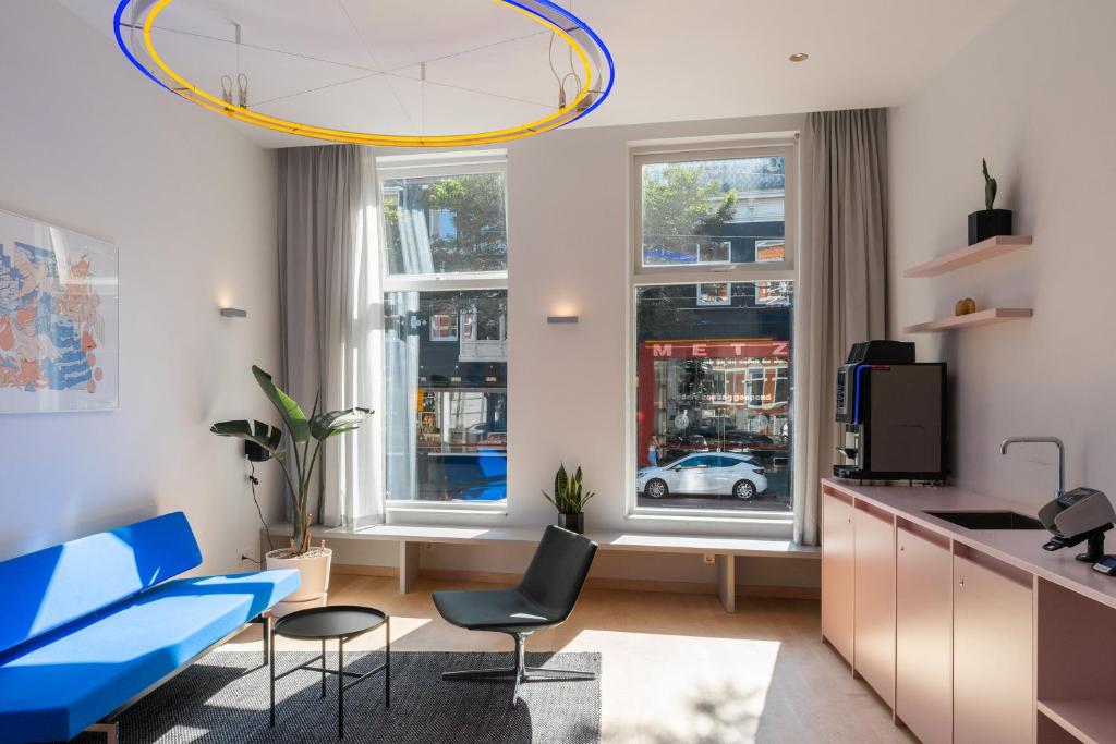 鹿特丹171. Urban Design Hotel的厨房以及带蓝色沙发和椅子的客厅。