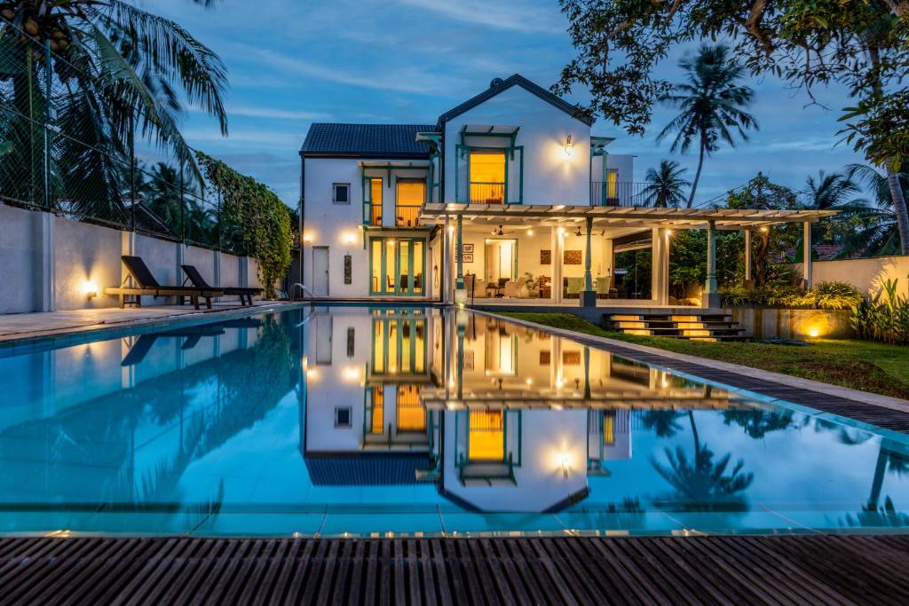 尼甘布Astig Villa - Negombo的一座晚上设有游泳池的房子