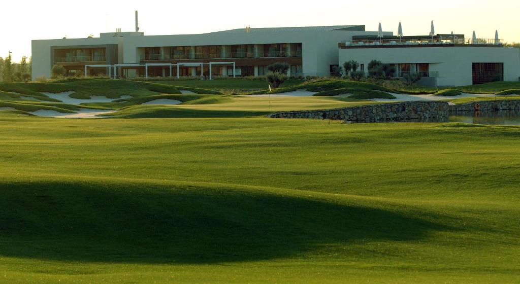 阿尔卡拉德荷那利斯塞尔科泰尔艾西恩高尔夫酒店的一座带建筑和绿色的高尔夫球场