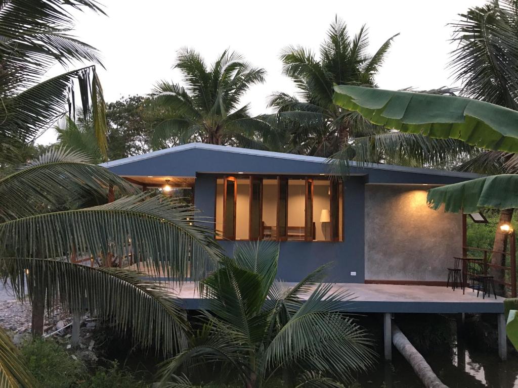 Ban Mo Kaeng TaekCOCO HOME Homestay(โคโค่โฮม)的棕榈树海滩上的房子